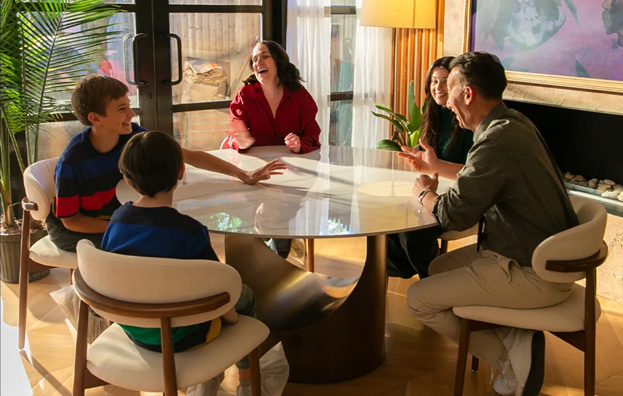 Guests and Friends Sitting Around Povison Bid Round Dining Table in the a Big House